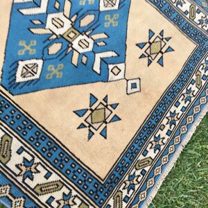 May include: A blue and beige patterned rug with a geometric design. The rug has a fringe border.