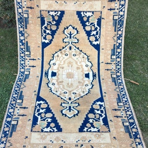 May include: A vintage rug with a beige background and a blue border. The rug has a traditional Persian design with intricate floral patterns and geometric shapes.
