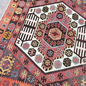 May include: A traditional Turkish rug with a geometric pattern in shades of red, blue, green, and white. The rug features a central medallion with a repeating pattern of hexagons and stars.