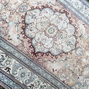 Peut inclure: Un tapis vintage avec un motif floral dans des tons de rose, marron et bleu. Le tapis a un aspect d&eacute;lav&eacute; et est fait d'un mat&eacute;riau doux et tiss&eacute;.
