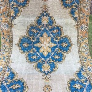 May include: A rectangular, vintage-style rug with a central medallion design. The rug features a light gray background with ornate blue and gold floral patterns. The border is a darker gold color, adding contrast.