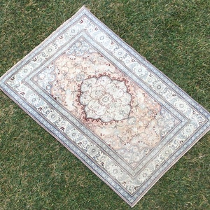 Peut inclure: Un tapis vintage avec un motif floral dans des tons beige, marron et bleu. Le tapis a un m&eacute;daillon central avec un motif floral et une bordure avec un motif r&eacute;p&eacute;titif.