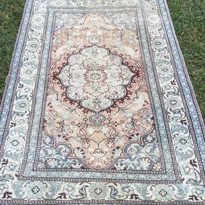 Peut inclure: Un tapis vintage avec un motif floral dans des tons de rose, bleu et marron. Le tapis a une bordure avec un motif r&eacute;p&eacute;titif.