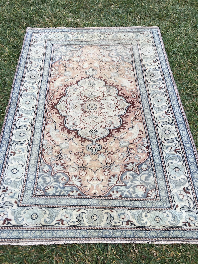 Peut inclure: Un tapis vintage avec un motif floral dans des tons de rose, bleu et marron. Le tapis a une bordure avec un motif r&eacute;p&eacute;titif.