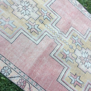 May include: A rectangular, vintage-style rug with a faded, distressed appearance. The rug features a central design in shades of peach and beige, with geometric patterns and floral motifs. The border is a darker peach color with repeating floral elements.