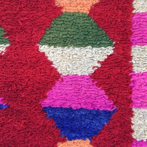 Puede incluir: Primer plano de una alfombra colorida y texturizada con formas geom&eacute;tricas en tonos rojos, verdes, blancos, rosas, azules y naranjas.