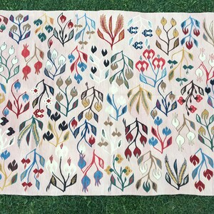 Puede incluir: Una alfombra rosa con un patr&oacute;n floral. La alfombra presenta una variedad de colores, incluyendo rojo, azul, verde, amarillo y blanco. Las flores son estilizadas y abstractas, y la alfombra tiene un aspecto tejido a mano.