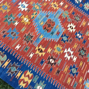 Puede incluir: Una alfombra colorida con un patr&oacute;n geom&eacute;trico en tonos rojos, azules, amarillos y marrones. La alfombra tiene un dise&ntilde;o tradicional con detalles intrincados.