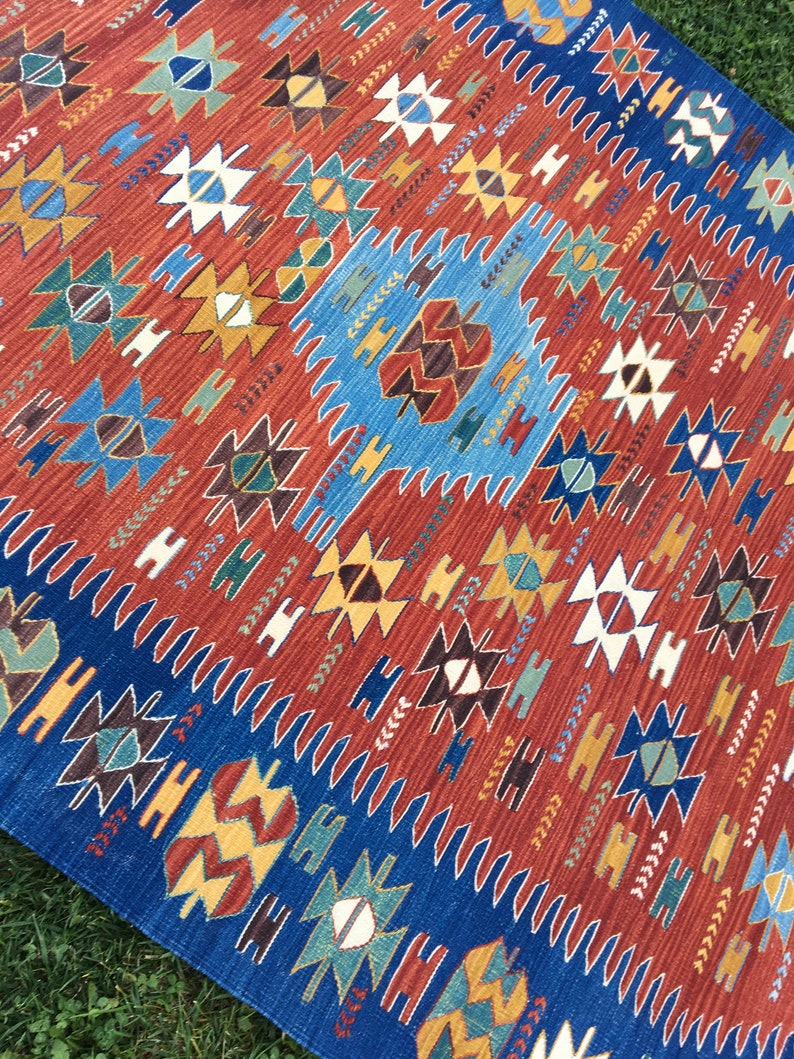 Puede incluir: Una alfombra colorida con un patr&oacute;n geom&eacute;trico en tonos rojos, azules, amarillos y marrones. La alfombra tiene un dise&ntilde;o tradicional con detalles intrincados.