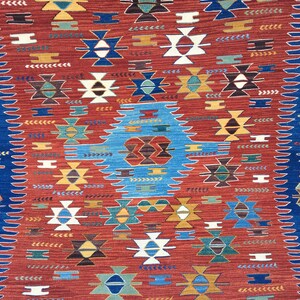 Puede incluir: Una alfombra roja, azul y blanca con dise&ntilde;os geom&eacute;tricos. La alfombra tiene un estilo tradicional y presenta una variedad de colores y formas.