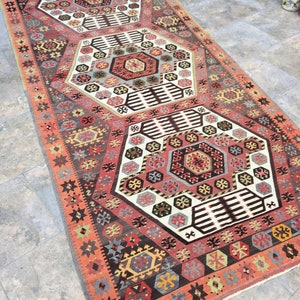 May include: A traditional Turkish rug with a geometric pattern in shades of red, brown, white, and blue. The rug features a repeating hexagonal design with intricate details.
