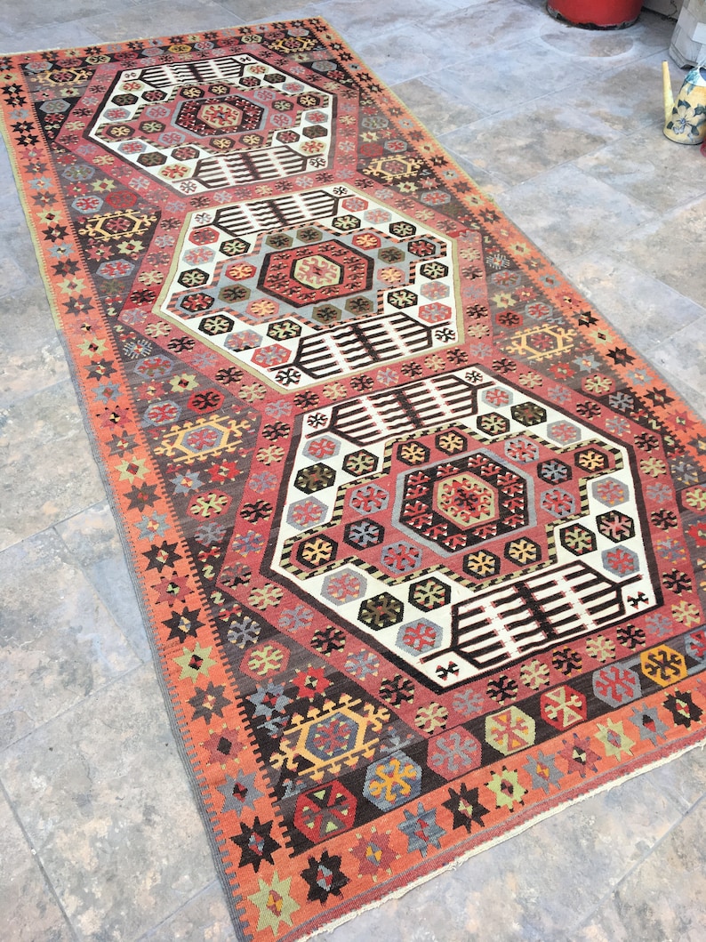 May include: A traditional Turkish rug with a geometric pattern in shades of red, brown, white, and blue. The rug features a repeating hexagonal design with intricate details.