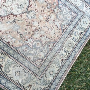 Peut inclure: Un tapis vintage de couleur bleu clair et beige. Le tapis pr&eacute;sente un motif floral avec un m&eacute;daillon central. Le tapis a une bordure &agrave; franges.