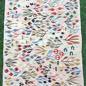 Puede incluir: Una alfombra rosa con un patr&oacute;n floral. La alfombra tiene un borde de flecos y presenta una variedad de colores, incluyendo rojo, azul, verde, amarillo y marr&oacute;n.