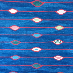 Puede incluir: Una tela azul con l&iacute;neas rojas y formas de diamantes de colores. Los diamantes est&aacute;n rellenos de varios colores, incluyendo amarillo, verde, rosa y azul.