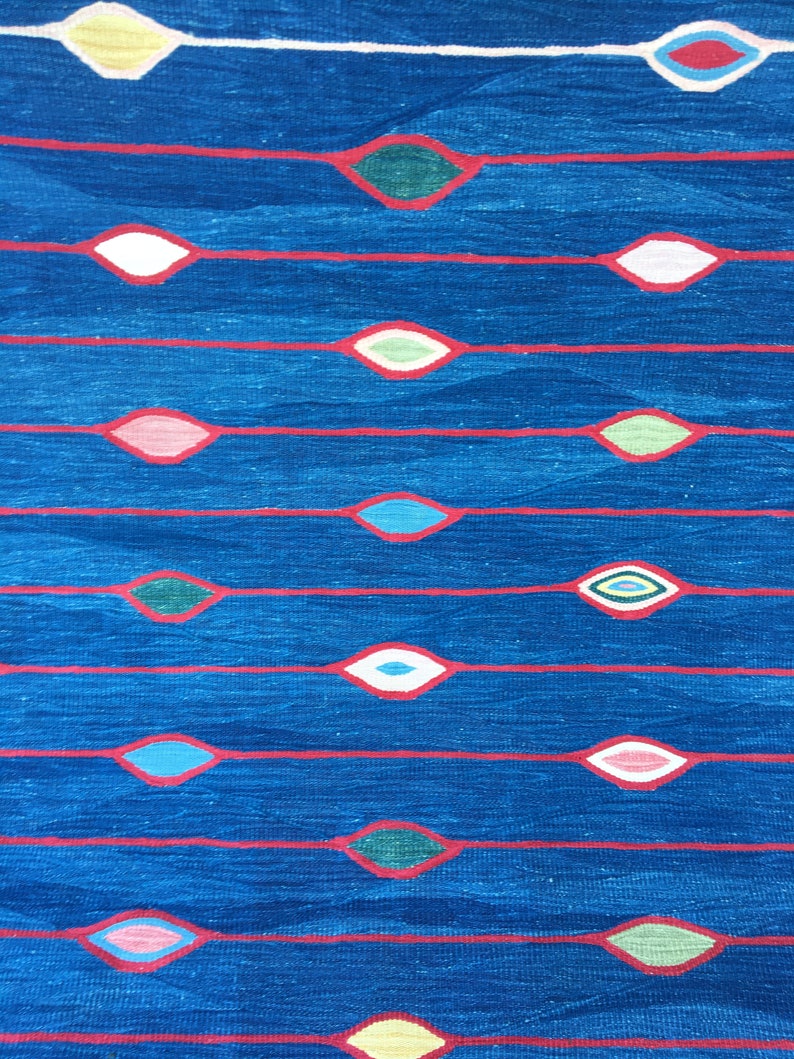 Puede incluir: Una tela azul con l&iacute;neas rojas y formas de diamantes de colores. Los diamantes est&aacute;n rellenos de varios colores, incluyendo amarillo, verde, rosa y azul.