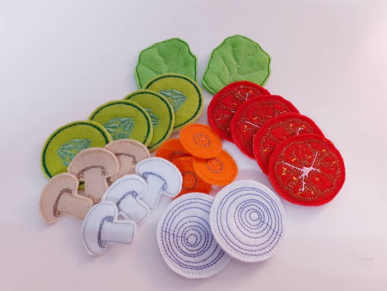 Puede incluir: Conjunto de juego de comida de fieltro con varias verduras y champi&ntilde;ones. El conjunto incluye dos hojas de lechuga verdes, cuatro rodajas de zanahoria naranja, cinco rodajas de tomate rojo, cuatro rodajas de champi&ntilde;&oacute;n blanco y dos rodajas de cebolla blanca.