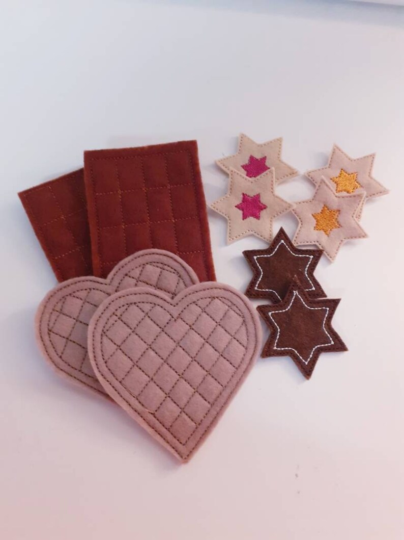 Puede incluir: Un conjunto de piezas de fieltro para una actividad de juego para ni&ntilde;os. El conjunto incluye dos rect&aacute;ngulos marrones, dos formas de coraz&oacute;n de color marr&oacute;n claro y cinco formas de estrellas de varios colores, incluyendo marr&oacute;n, rosa y amarillo.