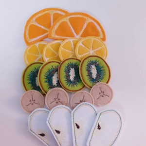 Puede incluir: Un conjunto de aplicaciones de fruta de fieltro, que incluyen rodajas de naranja, rodajas de kiwi y rodajas de pera. Las aplicaciones son perfectas para proyectos de manualidades, como coser, scrapbooking y hacer tarjetas.