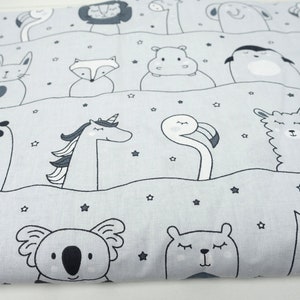 Könnte beinhalten: Grauer und weißer Stoff mit einem sich wiederholenden Muster aus verschiedenen Tieren, darunter ein Panda, ein Einhorn, ein Flamingo, ein Lama, ein Koala und ein Bär. Der Hintergrund ist hellgrau mit kleinen weißen Sternen.