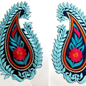 Puede incluir: Dos parches bordados con diseño de cachemira. Cada parche presenta una forma de lágrima azul oscuro con un diseño central de flor y hojas en rojo, turquesa y naranja. El diseño de cachemira está delineado con un borde de hojas azul claro y cuentas plateadas.