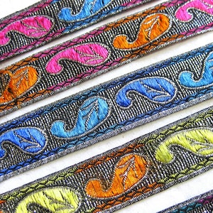 May include: Close-up of four different trims with a paisley design. The trims are silver, blue, orange, and pink on a black background.