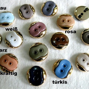 Può includere: Assortimento di 14 bottoni a due fori in vari colori, tra cui nero, bianco, marrone, rosa, blu e grigio. Ogni bottone ha un bordo dorato e un design ondulato.