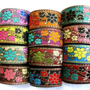 Op de afbeelding: Assortiment van kleurrijke geborduurde trim met bloemmotieven en gouden accenten. De trim is gerangschikt in een stapel van 10 stuks.