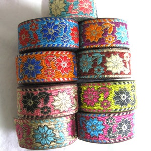 May include: Assortment of colourful floral patterned trim with gold accents. The trim is made of fabric and has a variety of colours, including blue, red, orange, pink, yellow, and green.