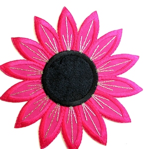 May include: A pink fabric flower with a black centre. The flower has a sparkly silver outline.