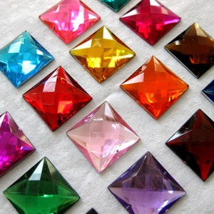 May include: Assortment of 14 square-shaped, faceted, iridescent glass gems in various colours, including pink, red, orange, yellow, green, blue, purple, and clear.