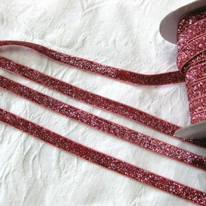 May include: A spool of pink glitter ribbon. The ribbon is velvet and has a sparkly finish.