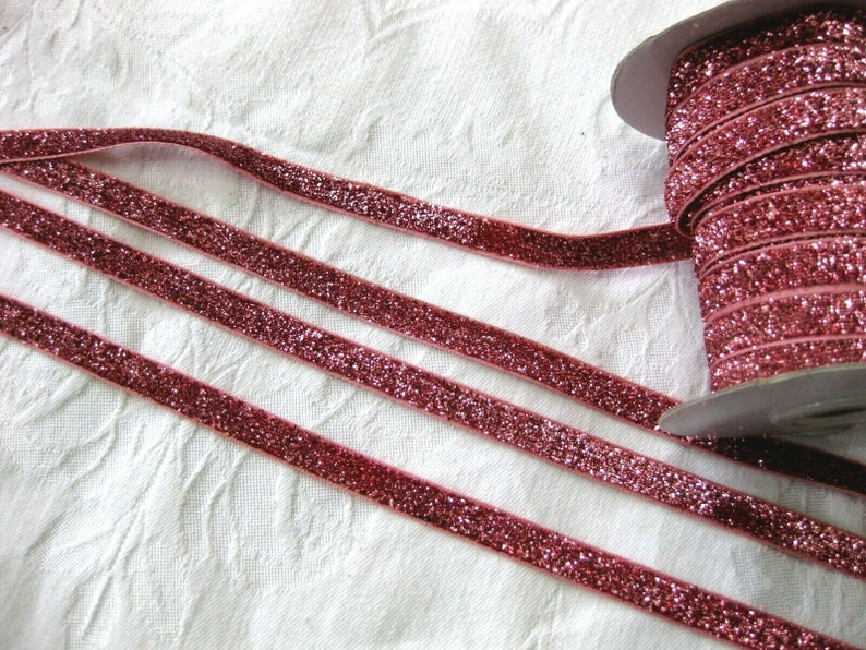 May include: A spool of pink glitter ribbon. The ribbon is velvet and has a sparkly finish.