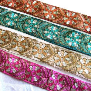 Op de afbeelding: Vier verschillende biesjes van geborduurde stoffen lint met bloemmotieven. De biesjes zijn in tinten oranje, turquoise, beige en roze.