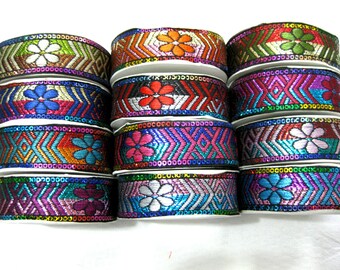 Op de afbeelding: Assortiment van kleurrijke, gepatroneerde trim met bloemmotieven. De trim is gemaakt van geweven stof met pailletten en metallic draden.