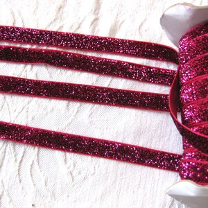 May include: A spool of pink glitter ribbon. The ribbon is rolled up and has a white label.