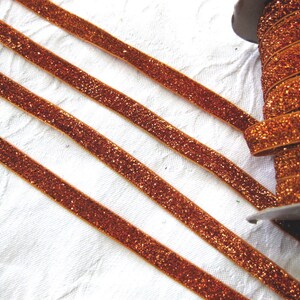 May include: A spool of orange glitter ribbon. The ribbon is a thin, flat strip with a sparkly finish.