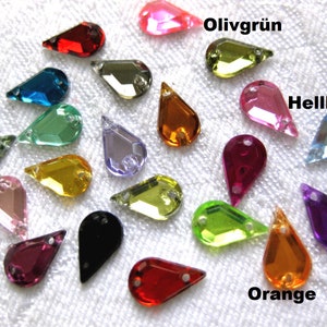 Könnte beinhalten: Sortiment von 18 tropfenförmigen Glas-Straßsteinen in verschiedenen Farben, darunter Rot, Orange, Gelb, Grün, Blau, Lila, Rosa, Schwarz und Klar. Die Strasssteine haben zwei Löcher oben zum Anbringen an Stoff oder andere Materialien.