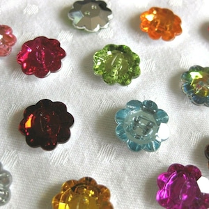 Op de afbeelding: Assortiment van kleurrijke bloemvormige knopen in verschillende kleuren, waaronder rood, groen, blauw, oranje en roze.