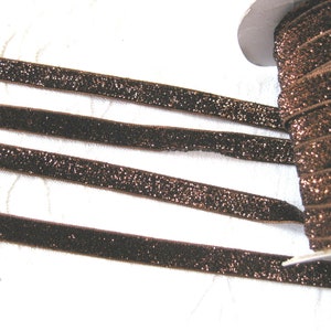 May include: Brown velvet ribbon with a sparkly finish. The ribbon is rolled up on a spool.