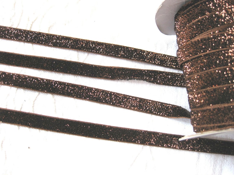May include: Brown velvet ribbon with a sparkly finish. The ribbon is rolled up on a spool.
