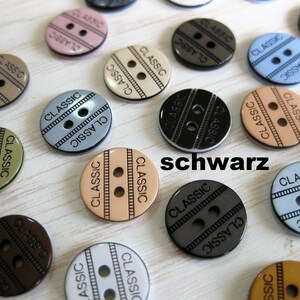 Könnte beinhalten: Sortiment aus zwei-Loch-Kunststoffknöpfen in verschiedenen Farben, darunter Braun, Beige, Schwarz, Blau und Grau. Die Knöpfe tragen den Aufdruck "CLASSIC".
