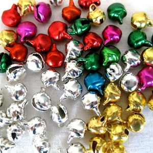 May include: A collection of small, metal bells in various colours, including silver, gold, red, green, blue, and pink. The bells have a rounded shape and a small loop at the top for hanging.