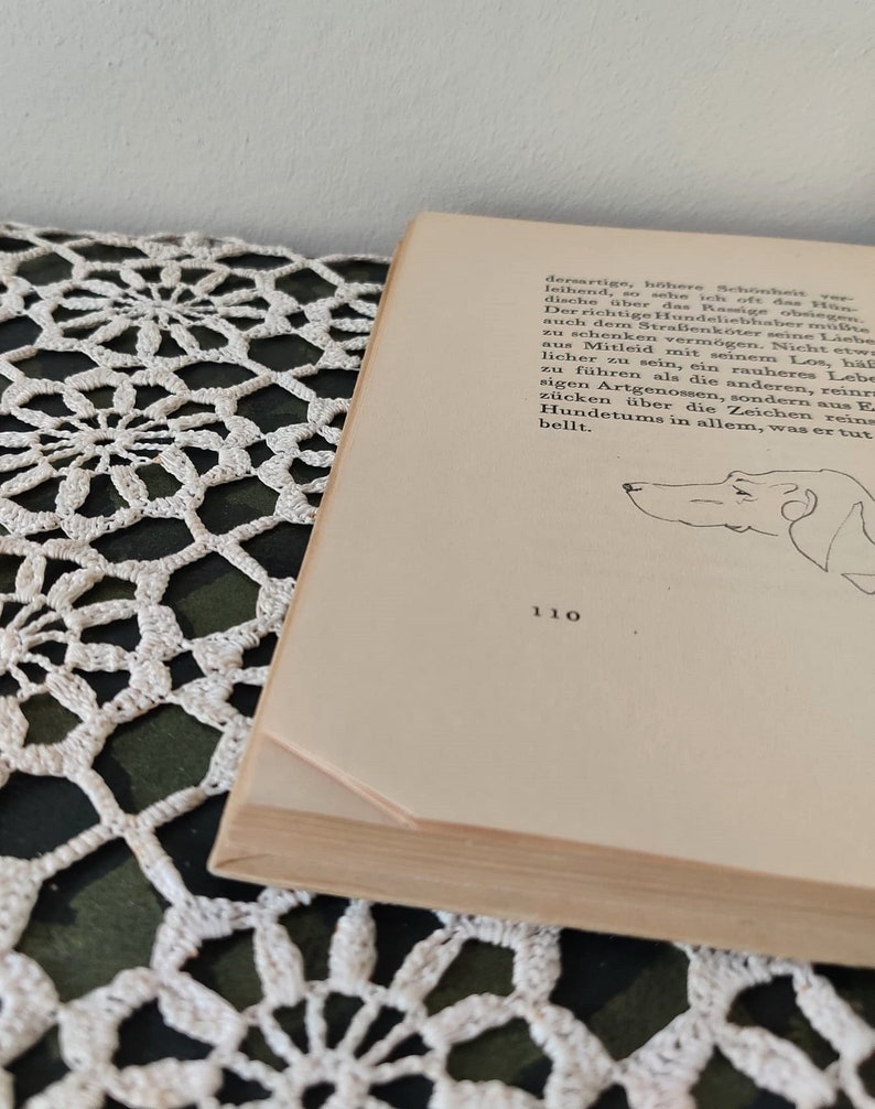 May include: A close-up of a page from a book with a black and white illustration of a dog's head. The text on the page reads "dersartige, h&ouml;here Sch&ouml;nheit leihend, so sehe ich oft das Hon dische &uuml;ber das Ramige obeig Der richtige Hundeliebhaber m&uuml;&szlig;te auch dem Stra&szlig;enk&ouml;ter seine Liebe zu schenken verm&ouml;gen. Nicht etw aus Mitleid mit seinem Los, h&auml;l licher zu sein, ein rauheres Lebe zu f&uuml;hren als die anderen, reinrs sigen Artgenossen, sondern aus E z&uuml;cken &uuml;ber die Zeichen reins Hundetums in allem, was er tut bellt." The page number is 110.