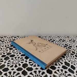May include: A vintage book titled "Hunde" by B. & P. Dolbin. The book cover features a black and white illustration of a dog. The book is bound in a blue cover with the title "Dolbin's Hunde" printed on the spine.