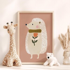 May include: A framed illustration of a hedgehog wearing a green scarf and holding a flower. A stuffed giraffe and a white polar bear toy are on the left and right. A vase of dried pampas grass is on the right.