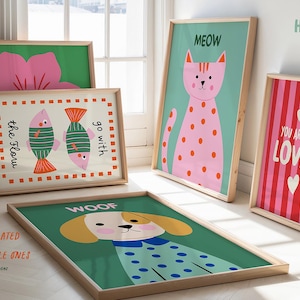 May include: A set of framed art prints with playful illustrations. The prints depict a pink flower, two fish, a pink cat with spots, a dog, and the text "You Are So Loved". The frames are made of light wood.