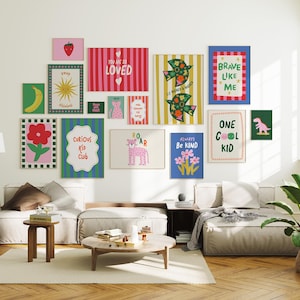 May include: A gallery wall of framed art prints with bright colours and cheerful designs. The prints include images of a banana, sun, flowers, and a dinosaur, with phrases such as "Curious Kid Club" and "Always Be Kind".