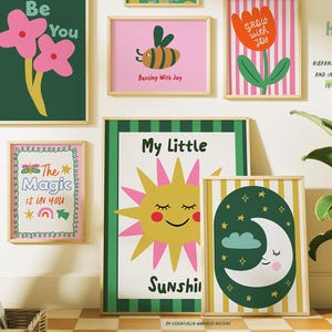 May include: A selection of framed art prints with vibrant illustrations and quotes. The prints depict flowers, a bee, a sun, and a moon. Text includes "Be You", "Buzzing with Joy", "Grow with Joy", "The Magic is in You", and "My Little Sunshine". The Happy Wall Club.