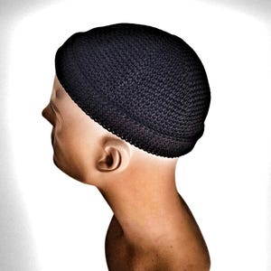 Könnte beinhalten: Eine dunkelmarineblaue Strickmütze, die auf einem Schaufensterkopf gezeigt wird. Die Mütze ist eng anliegend und bedeckt den oberen Teil des Kopfes. Das Strickmuster ist sichtbar, und die Mütze scheint aus einem weichen Material zu sein. Der Schaufensterkopf hat einen neutralen Hautton.